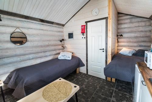 2 Betten in einem Zimmer mit Holzwänden in der Unterkunft Naali Mökki in Kilpisjärvi
