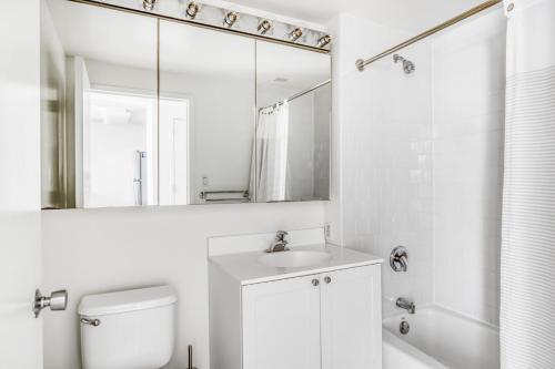 Un baño blanco con lavabo y espejo. en LIC 2BR w WD Elevator Doorman nr E River NYC-766, en Nueva York