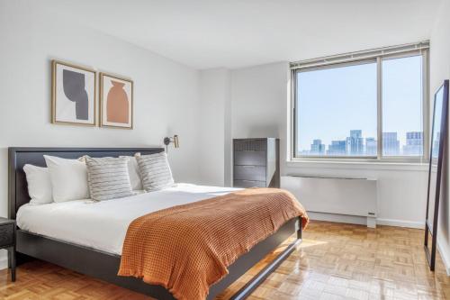 Un dormitorio con una cama y una ventana grande. en LIC 2BR w WD Elevator Doorman nr E River NYC-766, en Nueva York