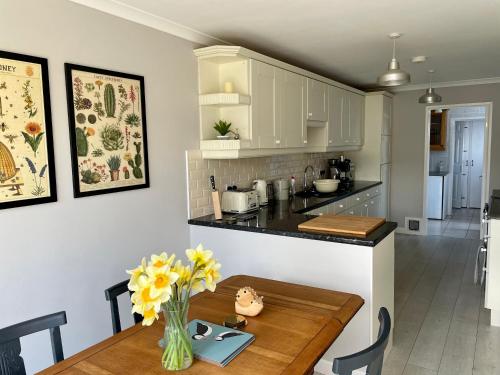 una cocina y comedor con una mesa con flores amarillas en Three bedroom holiday house Porthleven, Cornwall. Close to shops and beach, en Porthleven
