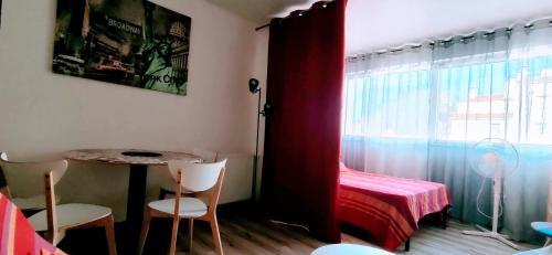 Cette petite chambre comprend une table et un rideau rouge. dans l'établissement Studio Sentosa bord de plage du Môle, au Cap d'Agde