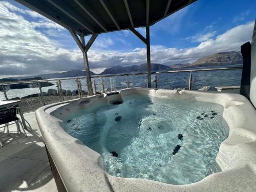a jacuzzi tub on a deck next to the water at Beach Houses with Hot Tubs in Glencoe