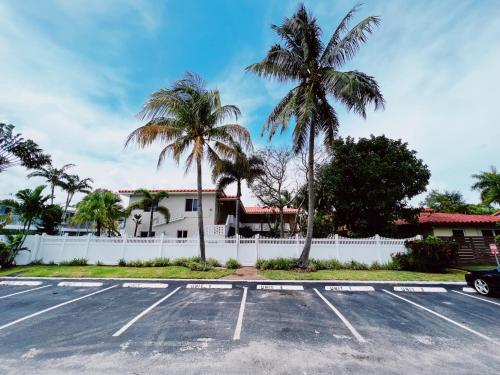 a parking lot in front of a house with palm trees at The Leeward Apartments By Lowkl in Fort Lauderdale