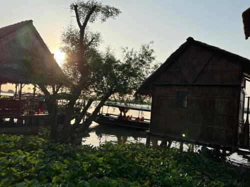a small house and a boat in a river at Happy Family Guesthouse in Vĩnh Long
