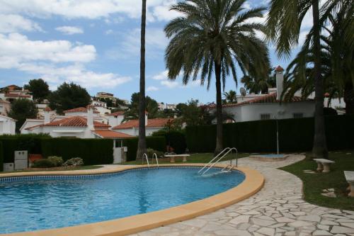 una piscina con palmeras y casas en Casa Anna, en Denia