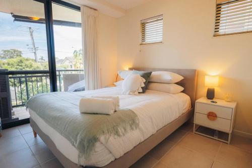 a bedroom with a bed with white pillows and a window at Waterfront Apt Maroochy River in Maroochydore