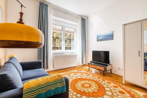 een woonkamer met een blauwe bank en een televisie bij Budapest Then & Now Apartment in Boedapest
