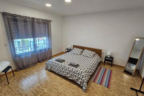 um quarto com uma cama e uma grande janela em Casa da Relva em Ponta Delgada