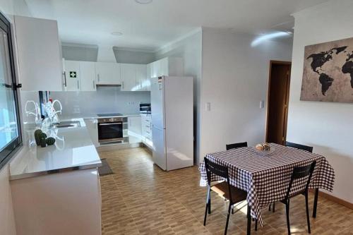 uma cozinha com uma mesa e um frigorífico branco em Casa da Relva em Ponta Delgada