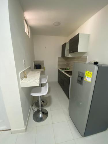 a small kitchen with a refrigerator and a stool at Cómodo apto 202 muy cerca a CC Unicentro Cúcuta in Cúcuta