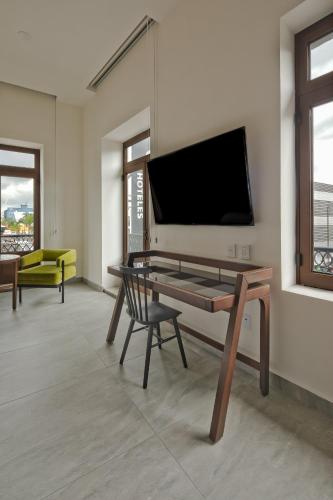 a living room with a table and a tv on a wall at Gamma Orizaba Grand Hotel de France in Orizaba