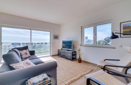 a living room with a couch and a tv and windows at FormosaFuzeta Seaview @Homesbyfc in Fuzeta