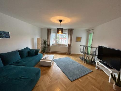 ein Wohnzimmer mit einem blauen Sofa und einem TV in der Unterkunft Paradiesisch Wohnen Bad Schwalbach in Bad Schwalbach