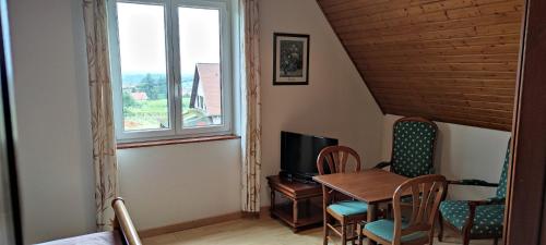 Habitación con mesa, sillas y ventana en Chambre d'hôtes de la tulipe, en Mittelbergheim