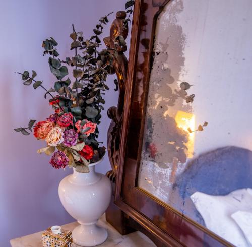 a vase with flowers in it next to a mirror at Casa Sofia Apt in Naples