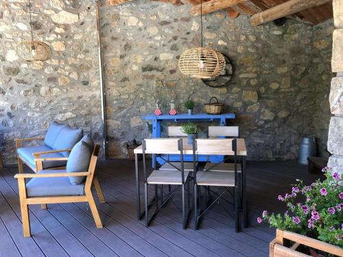 una mesa y sillas en un patio con una pared de piedra en Cal Lluch en Víllec