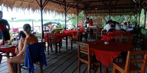 una mujer sentada en un restaurante con mesas y sillas rojas en Happy Family Guesthouse en Vĩnh Long