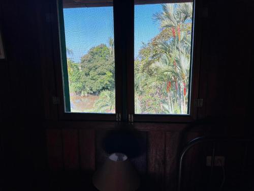 two windows in a room with a view of a palm tree at Hotel Veragua River House in Sierpe