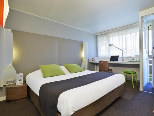 a bedroom with a large bed and a desk with a laptop at Campanile Hotel Senlis in Senlis