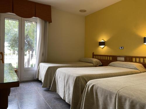 a hotel room with three beds and a window at La Colina in Geria