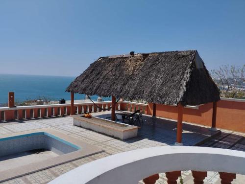 um resort com telhado de palha e uma piscina em Casa vista mar em Salina Cruz