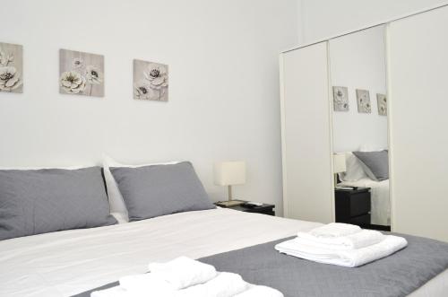 a bedroom with a bed with white sheets and mirrors at Pasiphae Heraklion Apartment in Heraklio Town