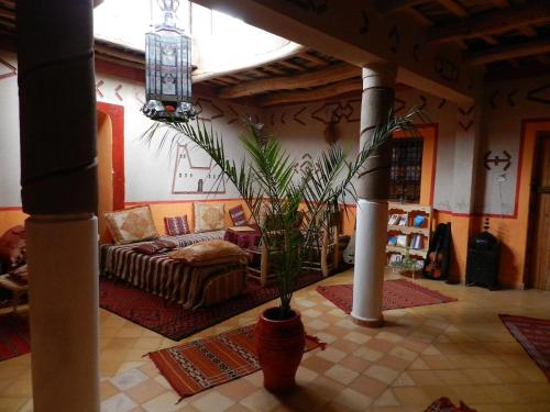 Riad Les 5 Lunes في Aït Idaïr: غرفة معيشة مع أريكة ونبات الفخار