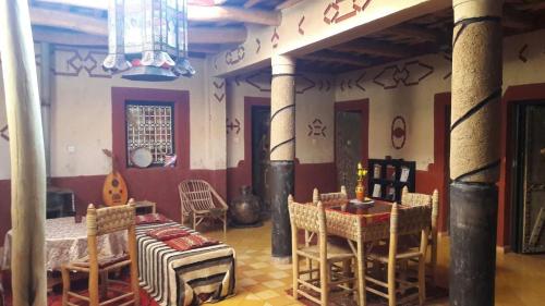 uma sala de estar com uma mesa e cadeiras num quarto em Riad Les 5 Lunes em Aït Idaïr