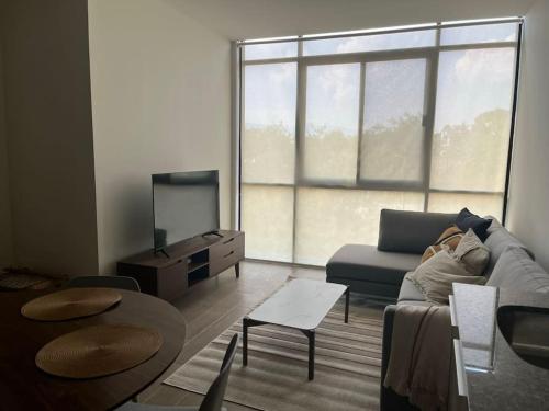 a living room with a couch and a tv at Departamento Tipo Loft, zona ajijic. in Jocotepec