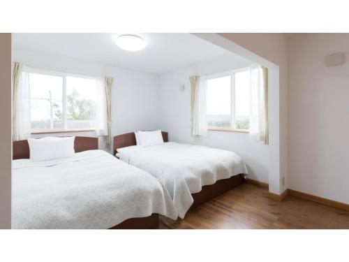 2 łóżka w białym pokoju z 2 oknami w obiekcie TEA TREES - Vacation STAY 86519v w mieście Tateyama