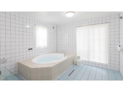 a white tiled bathroom with a tub and a window at TEA TREES - Vacation STAY 86519v in Tateyama
