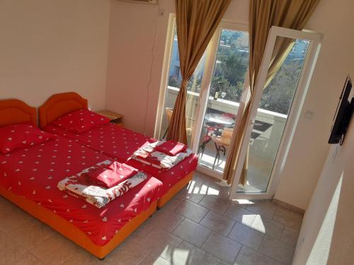 a bedroom with a red bed and a balcony at Perper in Sutomore