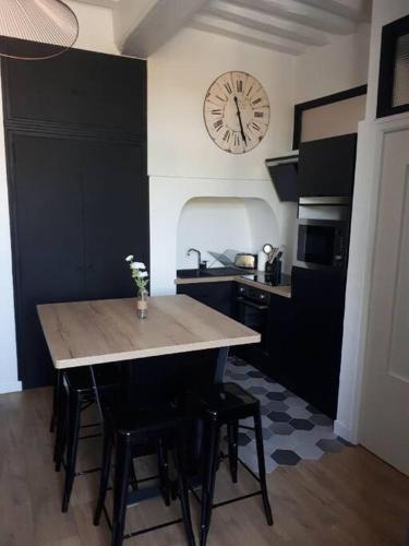 une cuisine avec une table et une horloge au mur dans l'établissement Appartement 4 personnes - Vannes intra-muros - Rue piétonne, à Vannes