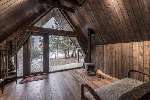 a room with a fireplace in a cabin with wooden walls at Aušrinės in Liškiava