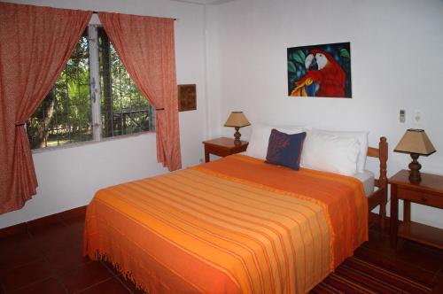 1 dormitorio con 1 cama con manta naranja en BlueBelize B&B, en Punta Gorda