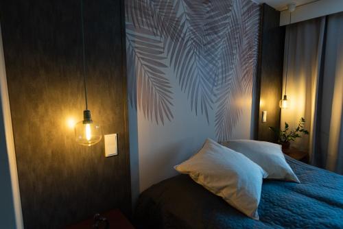 ein Schlafzimmer mit einem blauen Bett mit einem Palmenblatt-Wandbild in der Unterkunft Tyylikäs City-huoneisto in Tampere