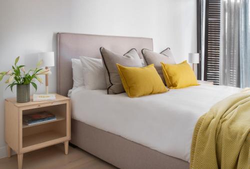 a white bed with yellow pillows and a night stand at Neighbourgood Old Cape Quarter in Cape Town