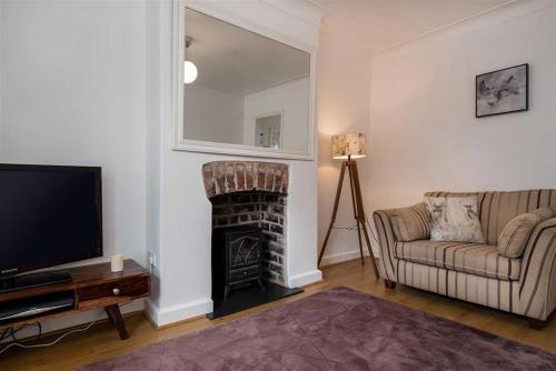 a living room with a couch and a fireplace at Lavender Terrace in Llandudno