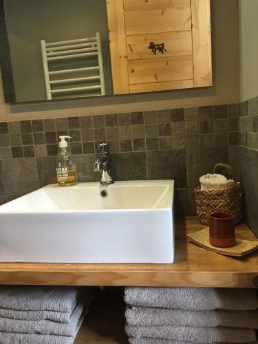 La salle de bains est pourvue d'un lavabo et de serviettes sous un miroir. dans l'établissement Gite Le Cerneux Haut Doubs, à La GrandʼCombe-Châteleu