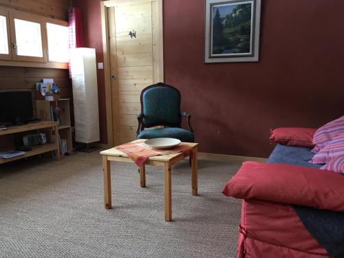 ein Wohnzimmer mit einem Stuhl und einem Tisch in der Unterkunft Gite Le Cerneux Haut Doubs in La GrandʼCombe-Châteleu