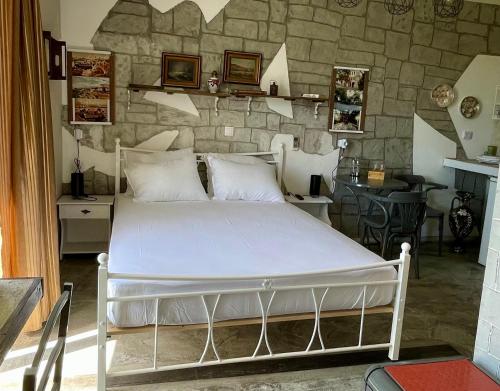 Cama blanca en habitación con pared de piedra en Efi studios en Kardámaina