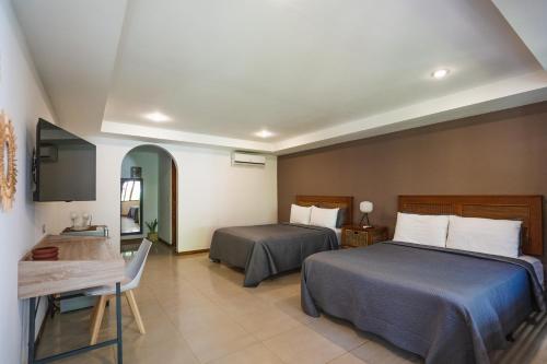 a hotel room with two beds and a desk at Hotel Arco Iris in Tamarindo