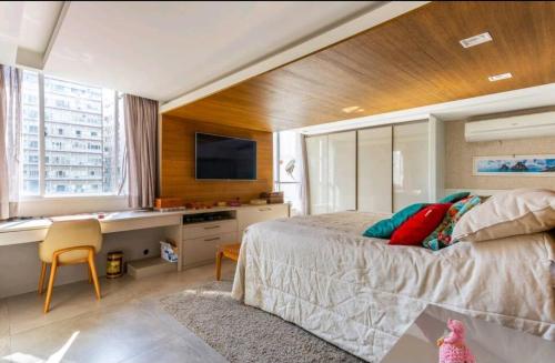 een slaapkamer met een bed en een bureau met een televisie bij Apartamento Luxuoso Frente Mar e MAC in Niterói