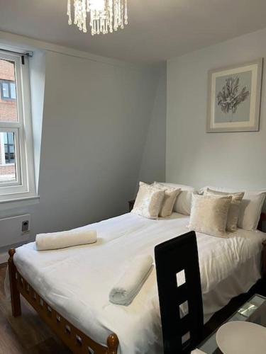 um quarto com uma cama grande com lençóis brancos e almofadas em 008- S2Premium location studio apartment central London em Londres