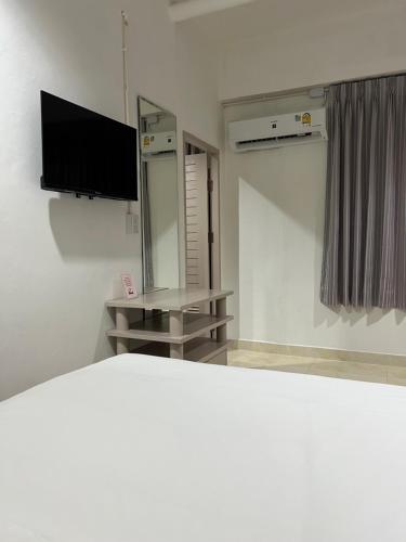 a room with a bed and a tv and a mirror at Mall Suites Hotel in Bangkok