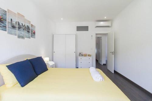 a white bedroom with a large bed with blue pillows at Casa Viveiros do Bairro Penha de França Lisboa in Lisbon