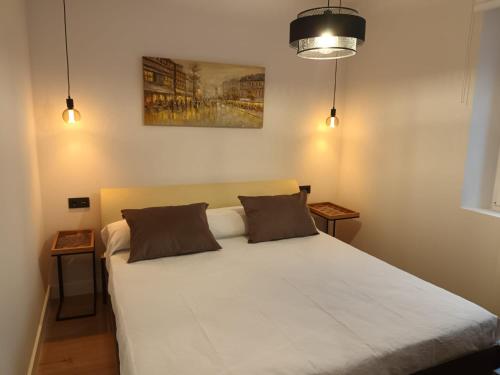 a bedroom with a large white bed with two pillows at Apartamento Roma 8 in León