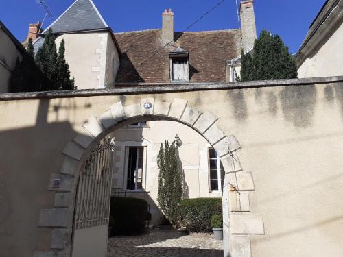 um arco que conduz a um edifício branco com um portão em Le Logis de Saint Cyr em Issoudun