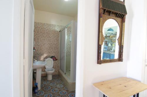 a bathroom with a toilet and a mirror on the wall at zina surf house in Oualidia