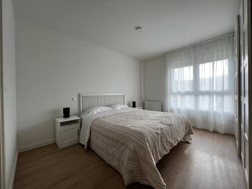 a white bedroom with a bed and a window at Apartamento Hoznayo in Entrambasaguas